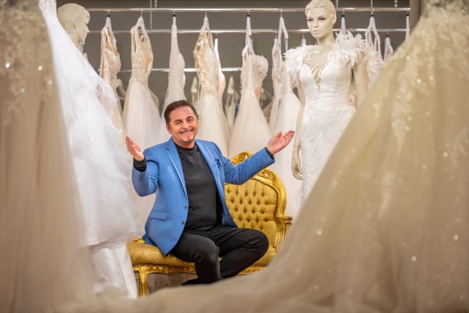 Mode-Profi Uwe Herrmann (59) sitzt freudestrahlend inmitten seiner weißen Brautkleider.