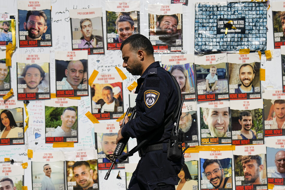 Ein israelischer Polizist geht an Bildern von Geiseln vorbei.