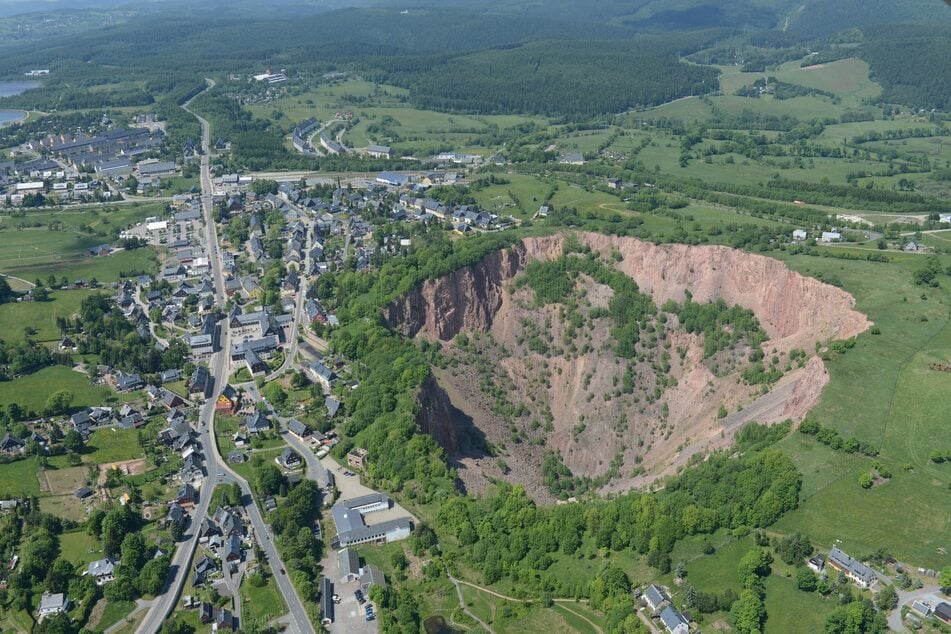 Rechts sieht man die Altenberger Pinge. Die trichterförmige Vertiefung ist ein typisches Relikt des Altbergbaus.