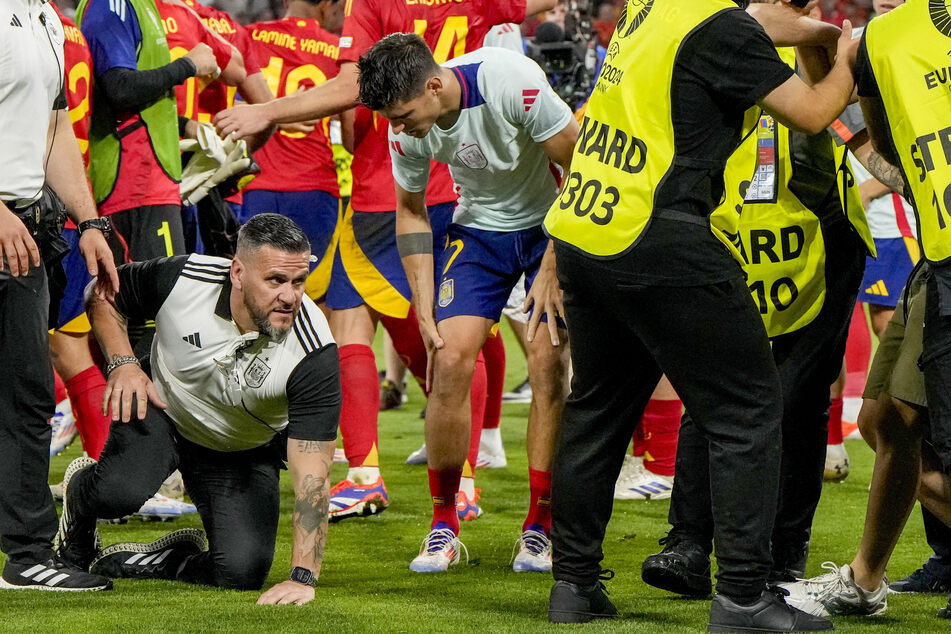 Spaniens Kapitän Álvaro Morata (31) hält sich das Knie, nachdem ein Ordner ihn auf der Jagd nach einem Flitzer erwischt hat.