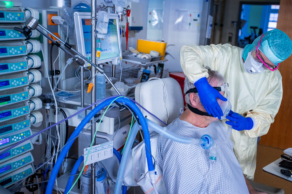 Eine Krankenpflegerin setzt in einer Intensivstation des Universitätsklinikums Greifswald einem Corona-Patienten die Beatmungsmaske auf.