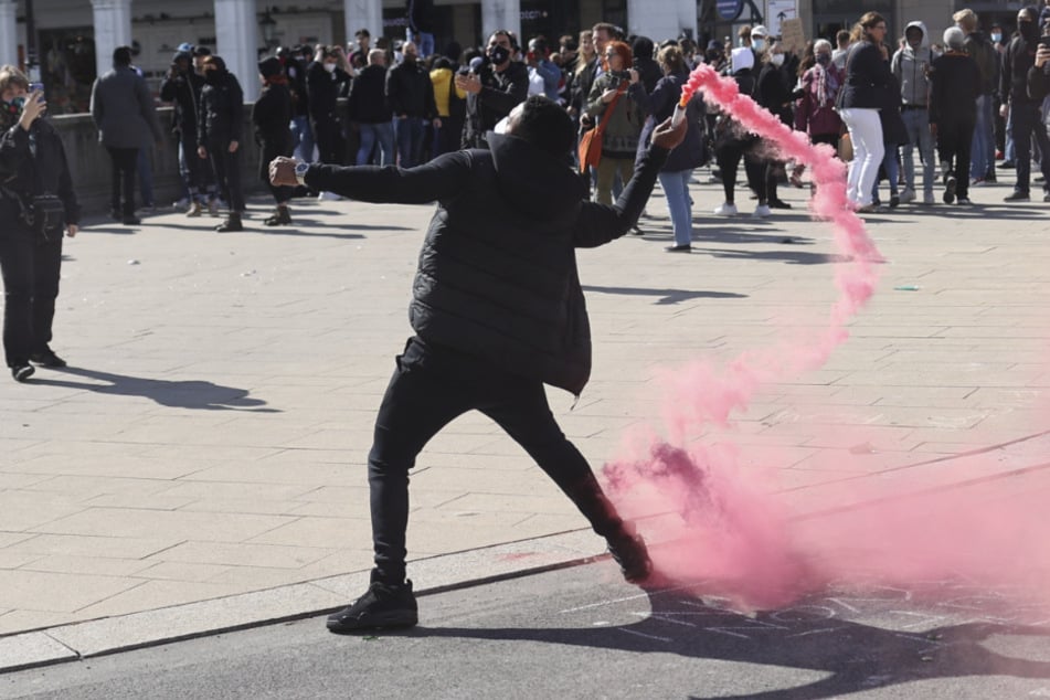 Ein Demonstrant wirft eine Rauchpatrone in Richtung der Polizeikräfte auf einer aufgelösten Demonstration.