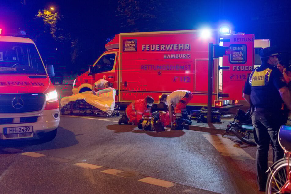 Die alarmierten Rettungskräfte versorgen den am Boden liegenden Radfahrer.