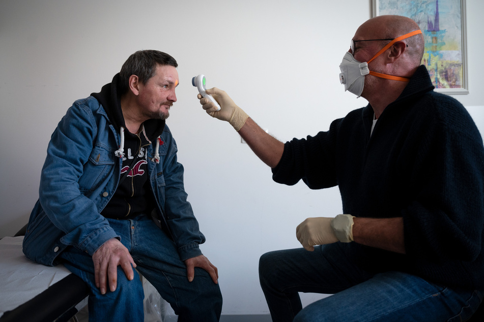 Mediziner Hans-Gerd Schmitz misst in seiner Sprechstunde im Fliednerhaus der Diakonie bei Thorsten Böhme mit einem kontaktlosen Fieberthermometer die Temperatur.