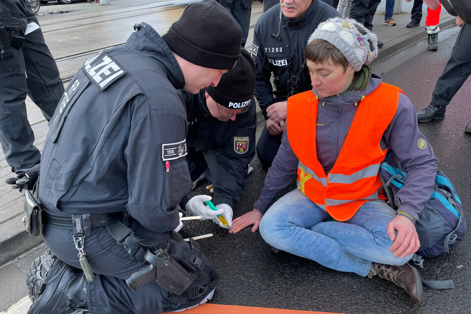 Mit einem speziellen Lösungsmittel mussten die Polizeibeamten die Klimaaktivisten von der Straße trennen.
