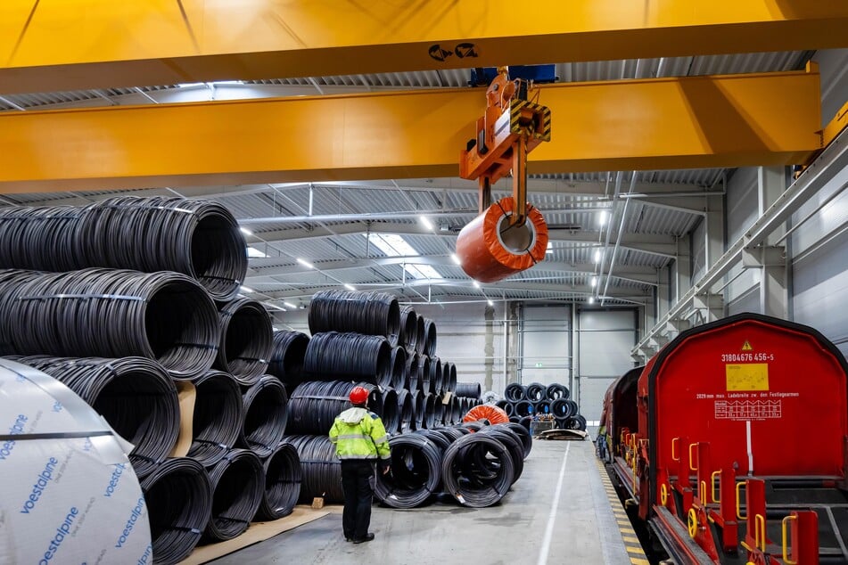 Mit einem Kran werden Draht- und Blechgebinde aus den Güterwaggons gehoben.