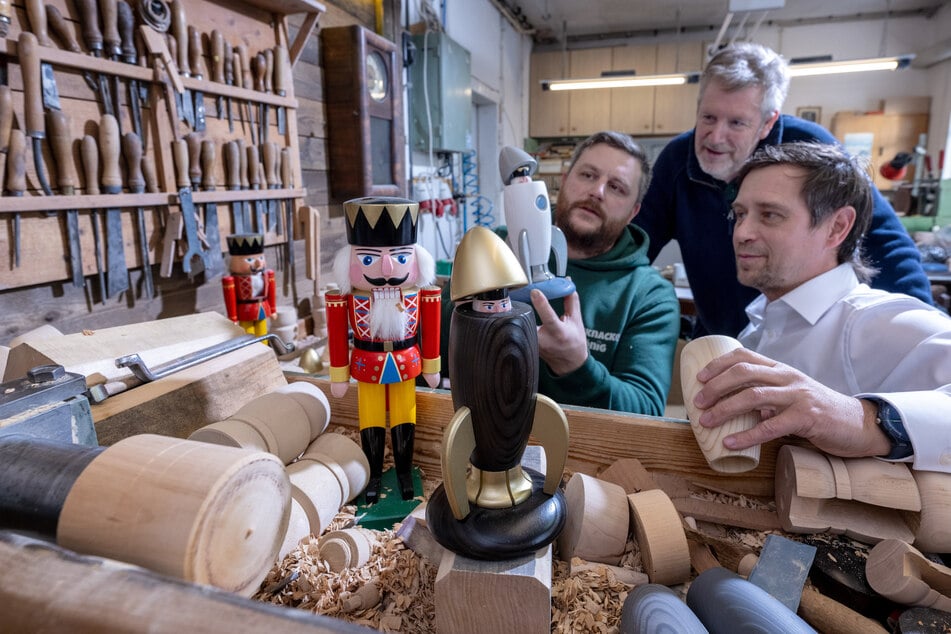 Holzspielzeugmacher Markus Füchtner (l.-r.) präsentiert in seiner Werkstatt in Seiffen gemeinsam mit den Partnern Wolfgang Braun von der "Denkstatt Erzgebirge" und Holger Kunze vom Fraunhofer IWU, eine neue Räucherrakete, in der Hightech-Material aus der Raumfahrt verbaut ist.
