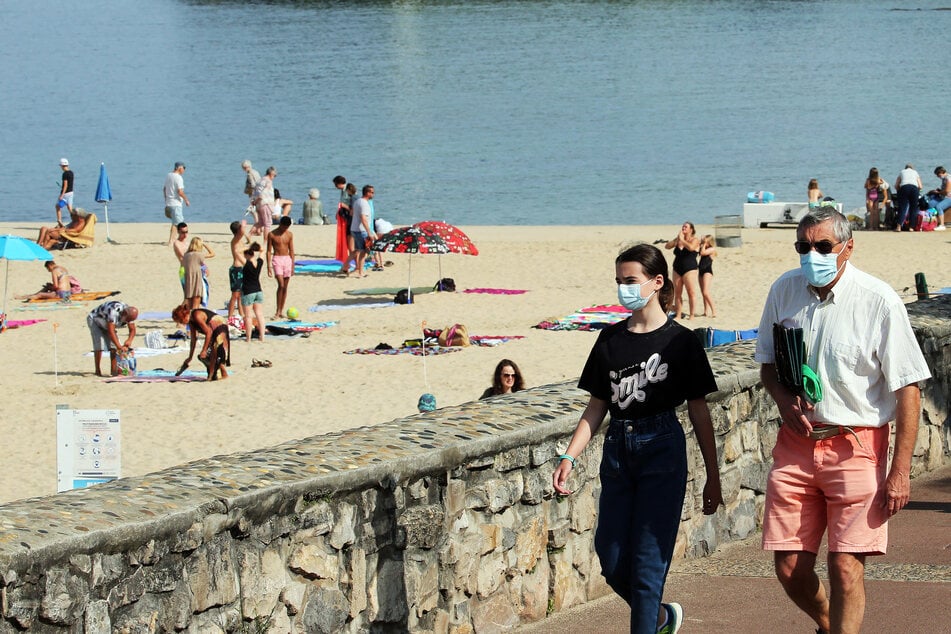 Menschen mit Mund-Nasen-Schutz am Strand in Saint-Jean-de-Luz im Südwesten Frankreichs.