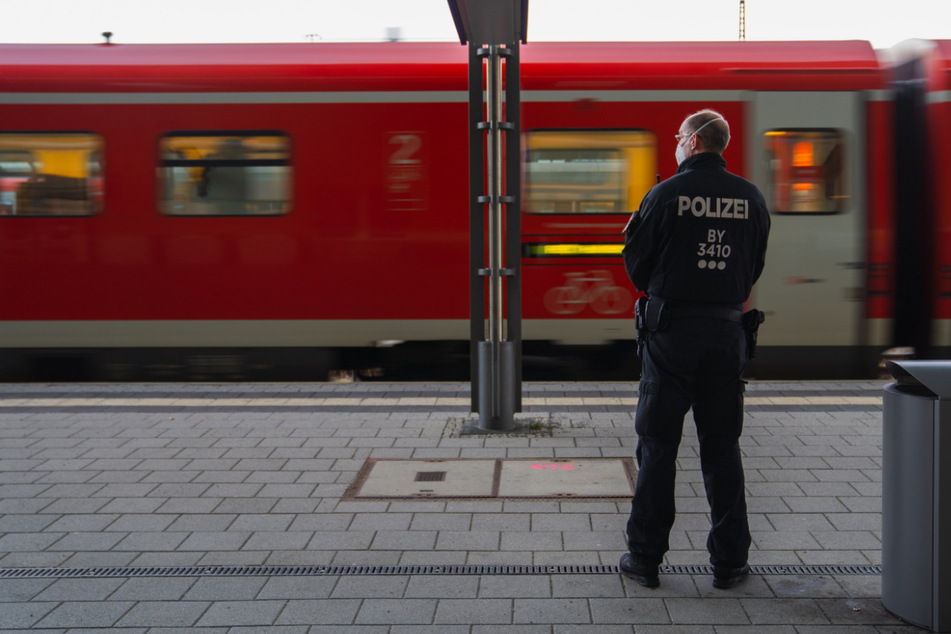 Ein Polizeibeamter blickt am Hofer Bahnhof auf die Insassen eines einfahrenden Zuges. Aufgrund der anhaltend hohen Inzidenzzahlen finden in Hof verstärkt Kontrollen statt.