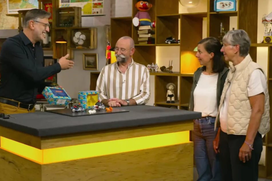 "Bares für Rares"-Verkäuferin Sarah (2.v.r.) hat zwei seltene Spielzeuge mit in die ZDF-Show gebracht, die ihr Bruder einst aus dem Sperrmüll rettete.