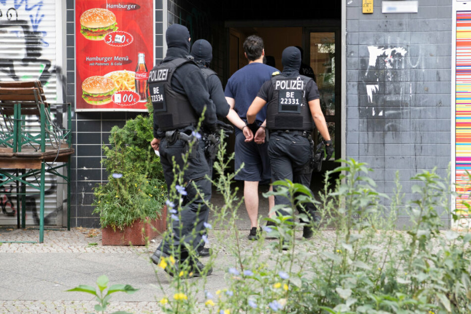 Polizeibeamte führen einen mit Handschellen gefesselten Mann in ein Haus in Berlin-Kreuzberg im Rahmen einer groß angelegten Razzia gegen Tatverdächtige aus der islamistischen Szene in verschiedenen Berliner Ortsteilen.