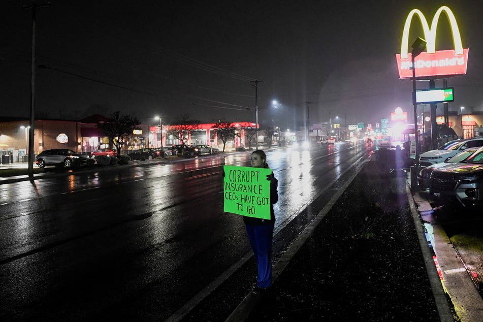 A person holds a sign reading "Corrupt Insurance CEOs Have Got to Go" near the McDonald's restaurant in Altoona, Pennsylvania, where Luigi Mangione was arrested as a suspect in the killing of UnitedHealthcare CEO Brian Thompson.