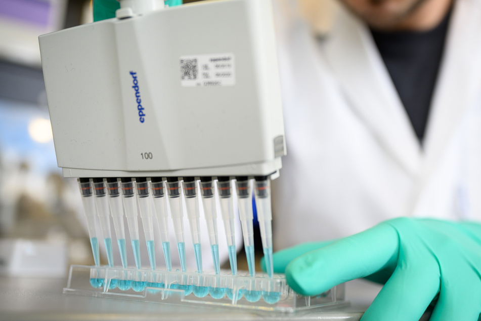 Ein Mann pipettiert in einem Labor eines biopharmazeutischen Unternehmens eine blaue Flüssigkeit.