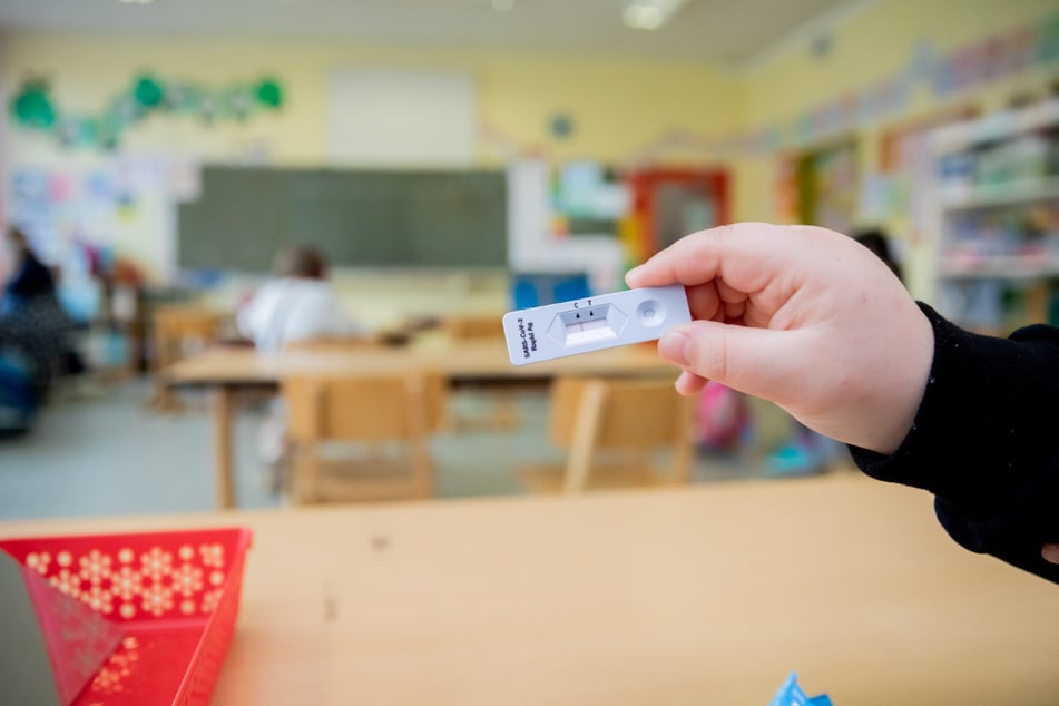 Ein Schüler hält bei einem Probelauf mit Corona-Schnelltests an der Grundschule in der Köllnischen Heide in Berlin-Neukölln seinen negativen Test in die Kamera.