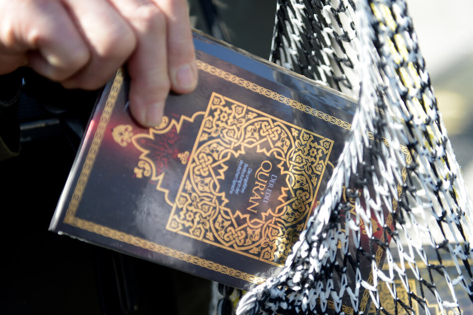 Ein Mann verteilt kostenlose Koran-Exemplare an Passanten.