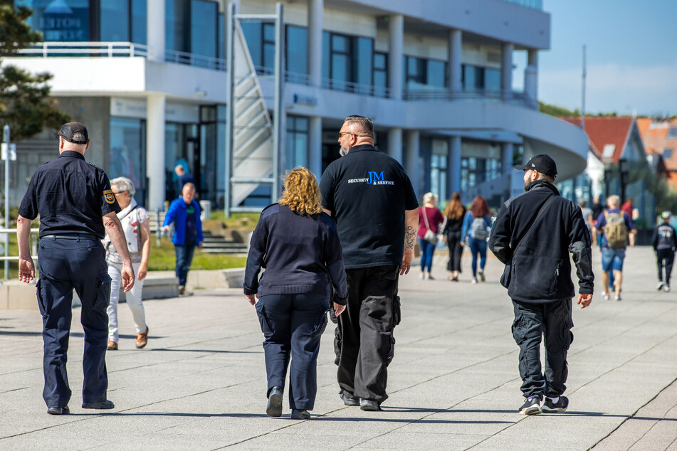 Mitarbeiter des Ordnungsamtes und einer privaten Sicherheitsfirma sind auf der Warnemünder Strandpromenade unterwegs.