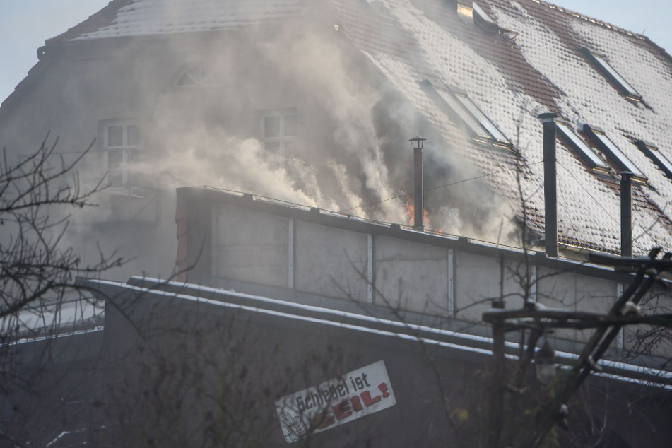 Die Flammen umhüllten das Dach des Gebäudes mit dicken Rauchschwaden.