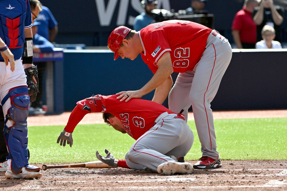 Los Angeles Angels third base coach Bill Haselman assists left fielder Taylor Ward, who was struck in the head by a pitch from Toronto Blue Jays pitcher Alek Manoah in the fifth inning at Rogers Centre.
