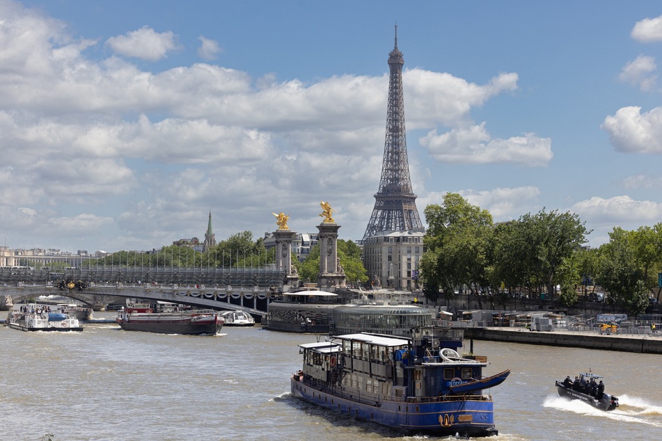 A Paris police (DOPC) boat (bottom L) makes its way past a cruise boat along the Seine River in Paris on Thursday.