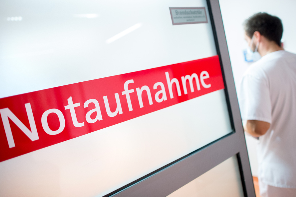 Ein Krankenpfleger in einem Krankenhaus geht durch eine Glastür mit der Aufschrift "Notaufnahme". Derzeit gibt es bei der Sieben-Tage-Inzidenz in Deutschland wenig Dynamik.
