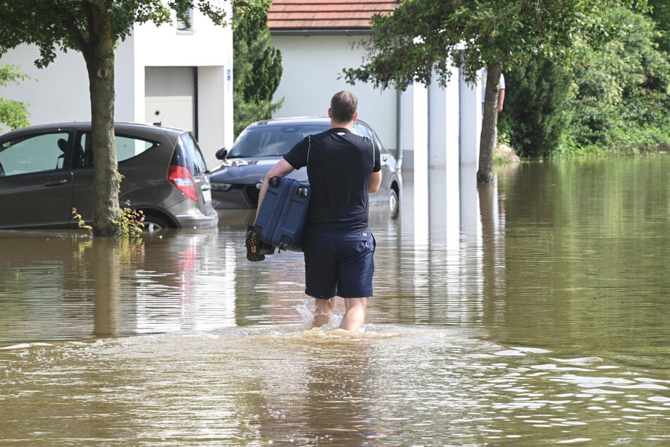 Dieser Mann watet mit einem Koffer unter dem Arm durch die Fluten in Fahrenzhausen (Bayern). Vermutlich, um sein Hab und Gut zu retten. Wer nicht raus muss, sollte aber lieber daheim bleiben.