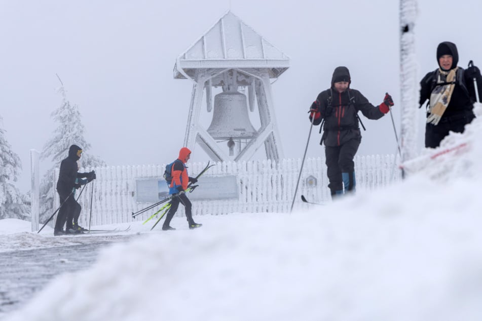 Trotz Sturm sind Skifahrer und Wanderer auf dem Gipfel unterwegs.