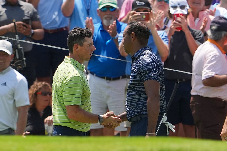 Rory McIlroy (l.) and Tiger Woods shake hands after finishing their round on the ninth green during the first round of the PGA Championship golf tournament.