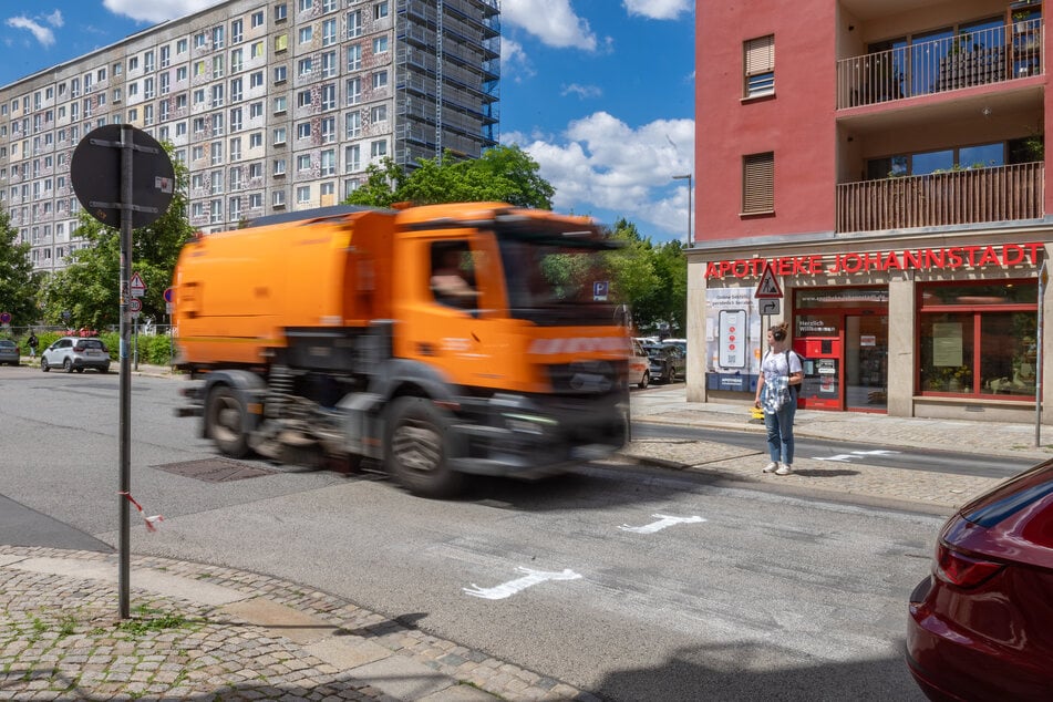 Die Müllabfuhr rauscht an Verkehrsinsel und Zebras vorbei.