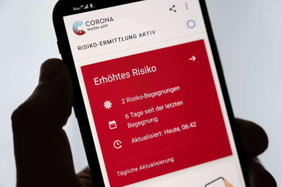 Ein Mann hält ein Smartphone in der Hand, auf dem die Corona-Warn-App der Bundesregierung ein erhöhtes Risiko anzeigt.