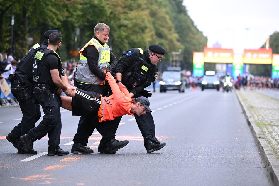 Ein Aktivist wird von Polizisten von der Straße getragen.