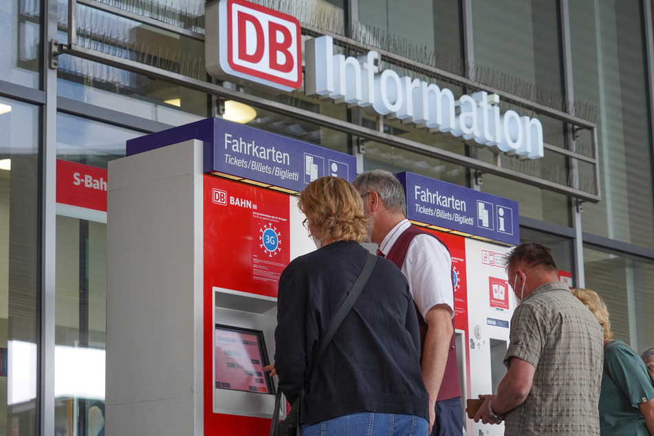 Reisende lösen an einem Automaten der Deutschen Bahn eine Zugfahrkarte.
