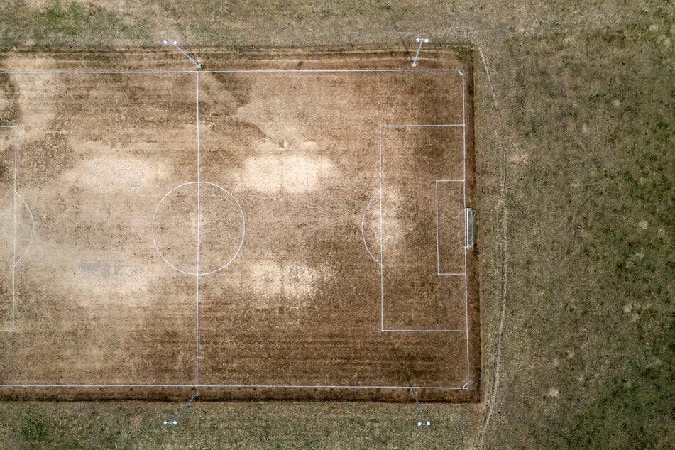 Luftaufnahme eines Fußballplatzes in der Schweiz, der sich aufgrund der Dürre in einem schlechten Zustand befindet.