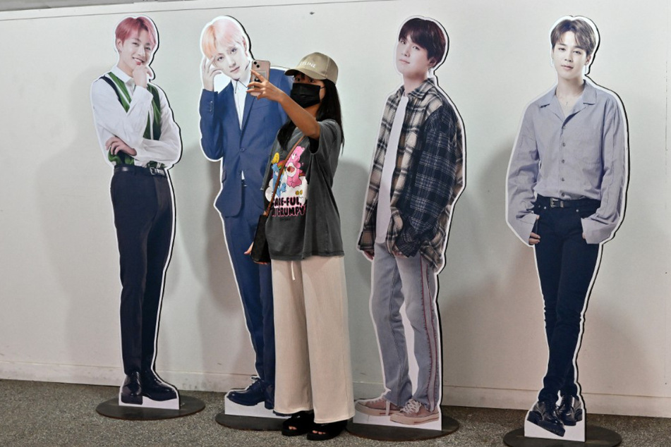 Eine Frau macht in einem Touristeninformationszentrum in Seoul ein Selfie mit Kartonausschnitten von Mitgliedern der populären Band BTS.