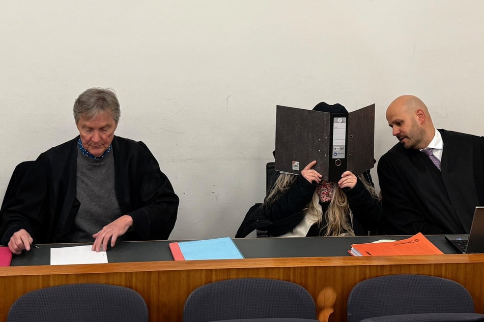 Die Angeklagte sitzt im Verhandlungssaal des Landgerichts zwischen ihren Verteidigern Thomas Hammer (l.) und Jan Astheimer (r.).