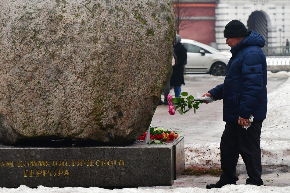 A man lays flowers for late Russian opposition leader Alexei Navalny at the monument to the victims of political repressions in Saint Petersburg, Russia on Saturday.