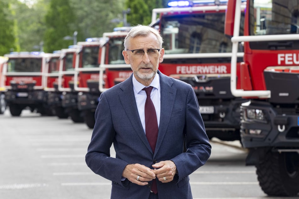 Sachsens Innenminister Armin Schuster (64, CDU) vor den Löschfahrzeugen.