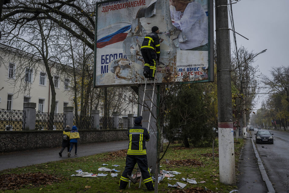 Feuerwehrleute entfernen russische Plakate in Cherson.