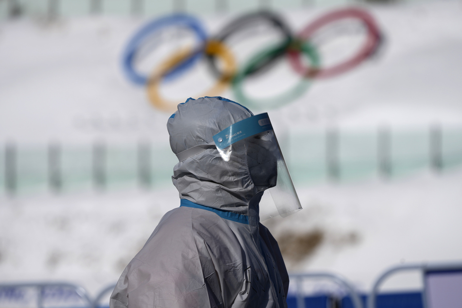 Ein Arbeiter in Schutzkleidung geht bei den Olympischen Winterspielen 2022 durch das Nationale Biathlonzentrum.