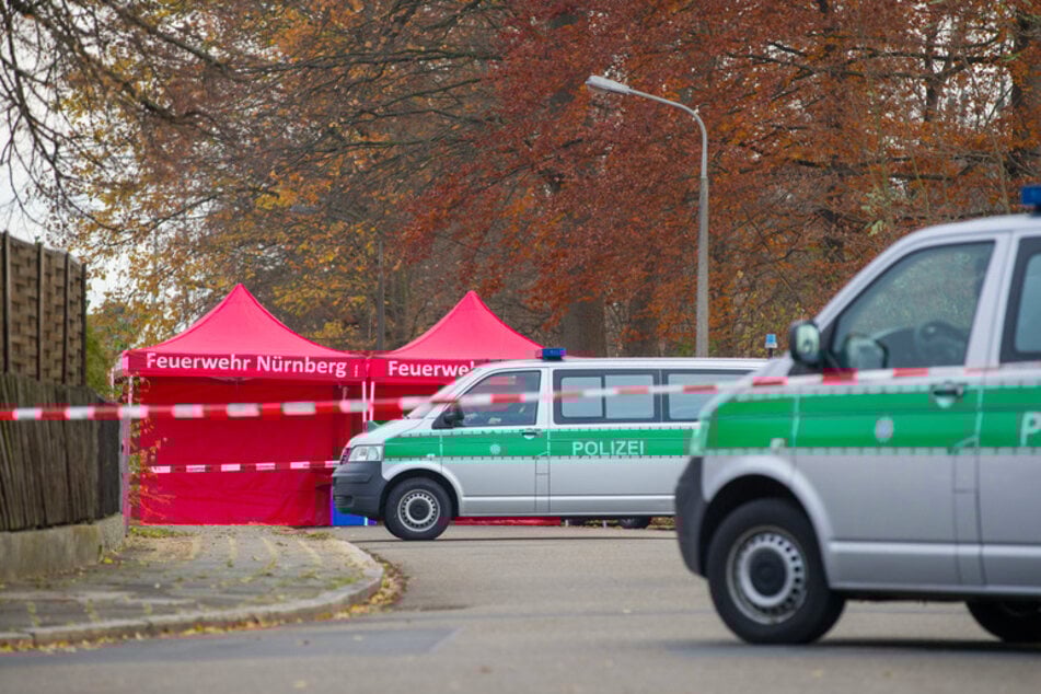 Polizisten bewachen die Zufahrt einer Straße, in der zuvor zwei Menschen erschossen wurden.