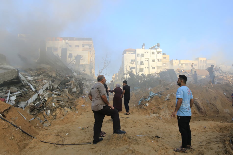 Menschen in Gaza-Stadt stehen nach israelischen Angriffen vor Trümmerhaufen.