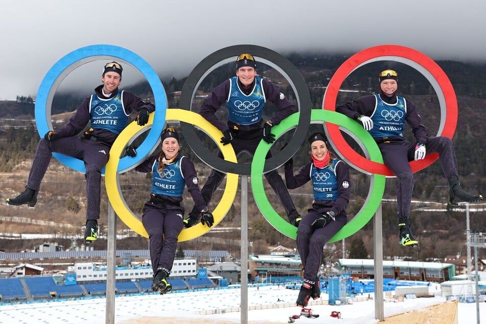 Deutschen Langläufer Florian Notz (33, v.l.), Katharina Hennig Dotzler (29), Friedrich Moch (25), Pia Fink (30) und Jakob Elias Moch (19) posieren auf den olympischen Ringen.