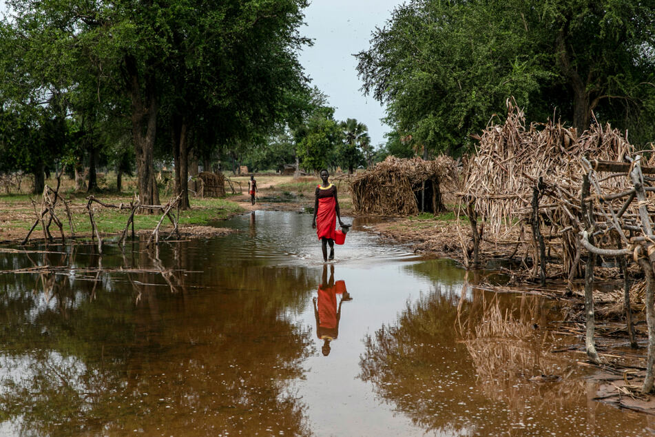 Eine Frau watet durch Hochwasser zwischen verlassenen Unterkünften im Dorf Majak Awar.