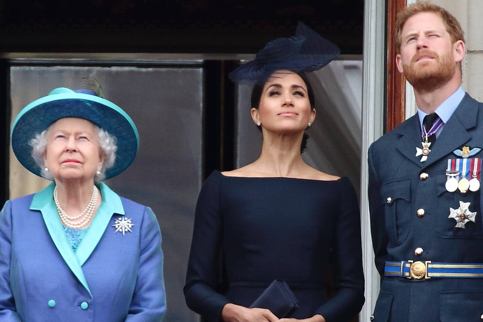 Those were the days: Queen Elizabeth II; her grandson, Prince Harry; and his wife, Duchess Meghan, stand on a balcony as Royal Air Force planes fly over Buckingham Palace in July 2018.