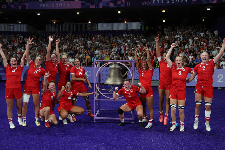 Team Canada ring the bell after winning their Olympic rugby sevens quarterfinal match against France.