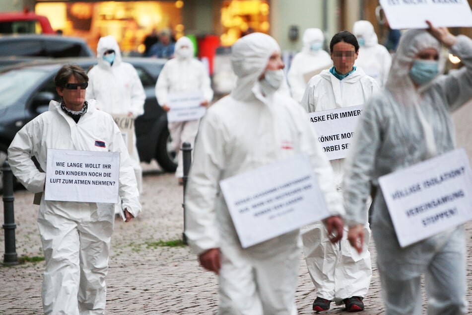Vor den Spaziergängen waren etwa 15 Personen mit weißen Schutzanzügen und Transparenten in Pirna unterwegs.