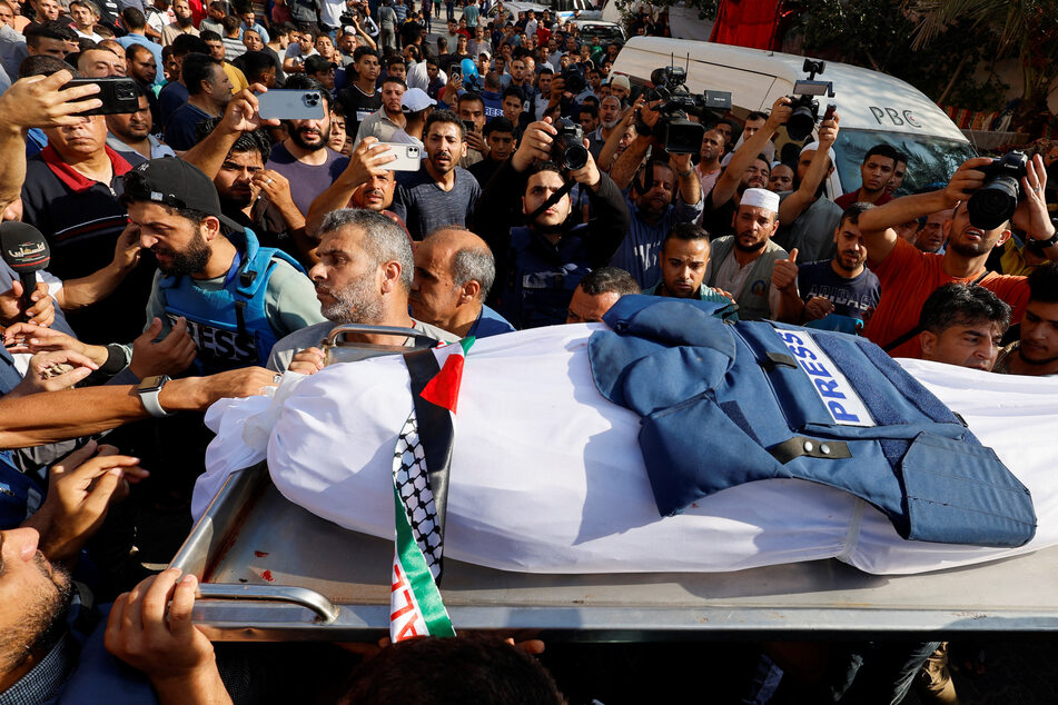 The body of Palestine TV reporter Mohammed Abu Hattab is carried by mourners in Gaza after an Israeli airstrike killed the journalist and members of his family.