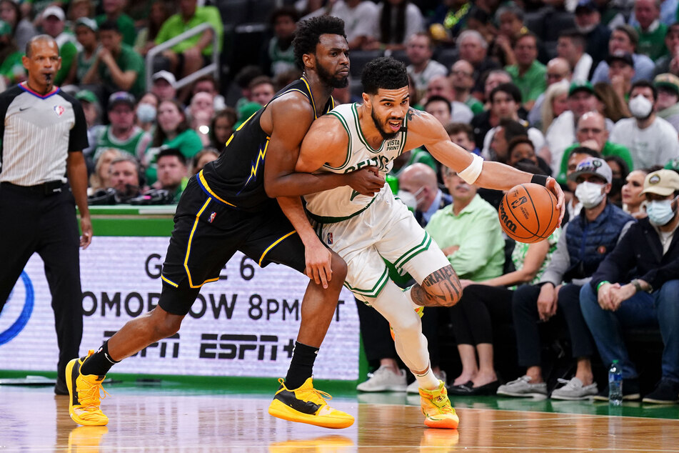 The Celtics' Jayson Tatum is challenged by Warriors forward Andrew Wiggins.