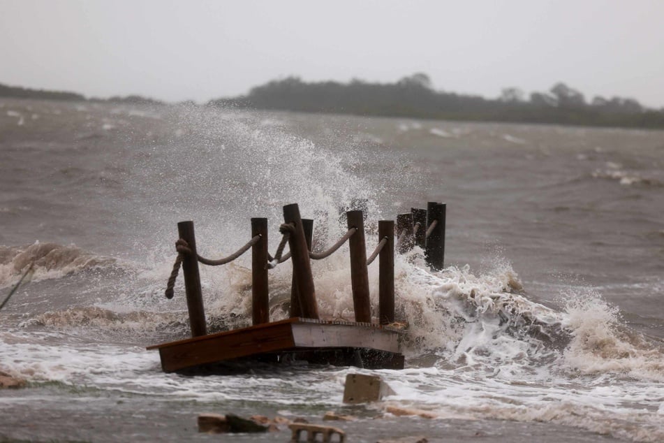 Surf crashes against a dock as high winds, rain, and storm surge from Hurricane Debby hit Cedar Key, Florida on Monday.