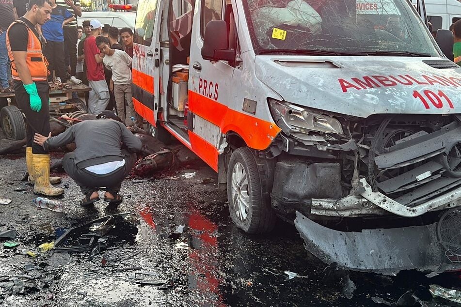 A dead horse lies on the ground as people gather around an ambulance damaged in an Israeli strike in front of Al-Shifa hospital in Gaza City on November 3, 2023.