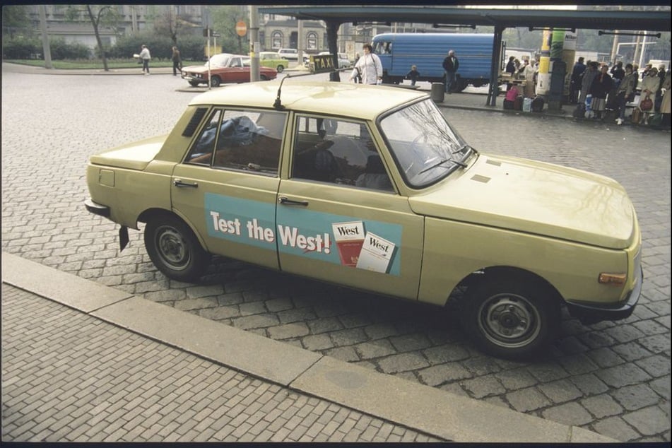 Bevor die ersten Daimler-Karossen den Taxi-Markt der Stadt fluteten, war auch der gute alte Wartburg noch als Chauffeursmobil im Einsatz. "Test the West" steht auf dem Taxi am Neustädter Bahnhof. Mit bunter Tabakwerbung für westdeutsche Marken konnte sich so mancher Autobesitzer in Wendezeiten etwas dazuverdienen.